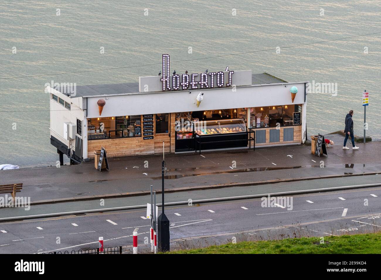 Roberto's Kiosk zum Mitnehmen an der Themse Mündung, Southend on Sea, Essex, Großbritannien. Person, die Hund an einem langweiligen, nassen Tag geht. Grauer Tag. Leer, ruhig während COVID 19 Stockfoto