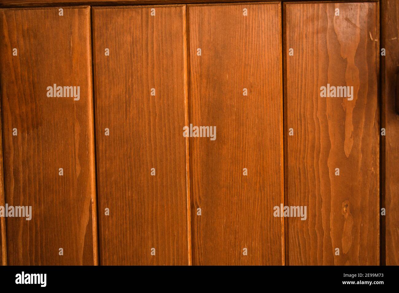 Gleichmäßig verteilte, satte, braune Paneele an einer Holztür füllen den Rahmen des Fotos; für den Einsatz als Hintergrund oder Präsentationsfolie. Stockfoto
