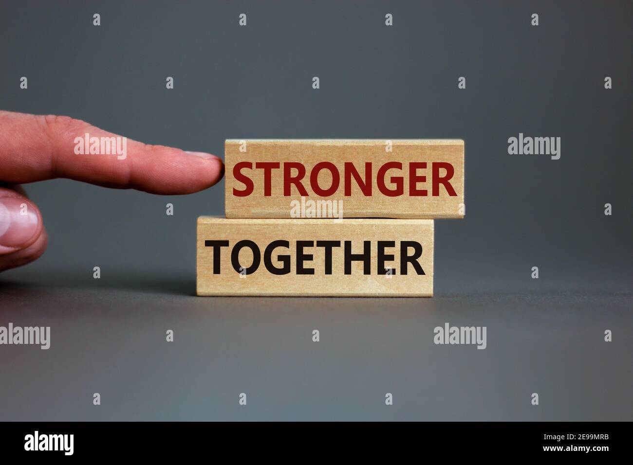 Stärker zusammen Symbol. Konzeptworte "stärker zusammen" auf Holzblöcken auf einem schönen grauen Hintergrund. Geschäftsmann Hand. Geschäft, Motivation Stockfoto