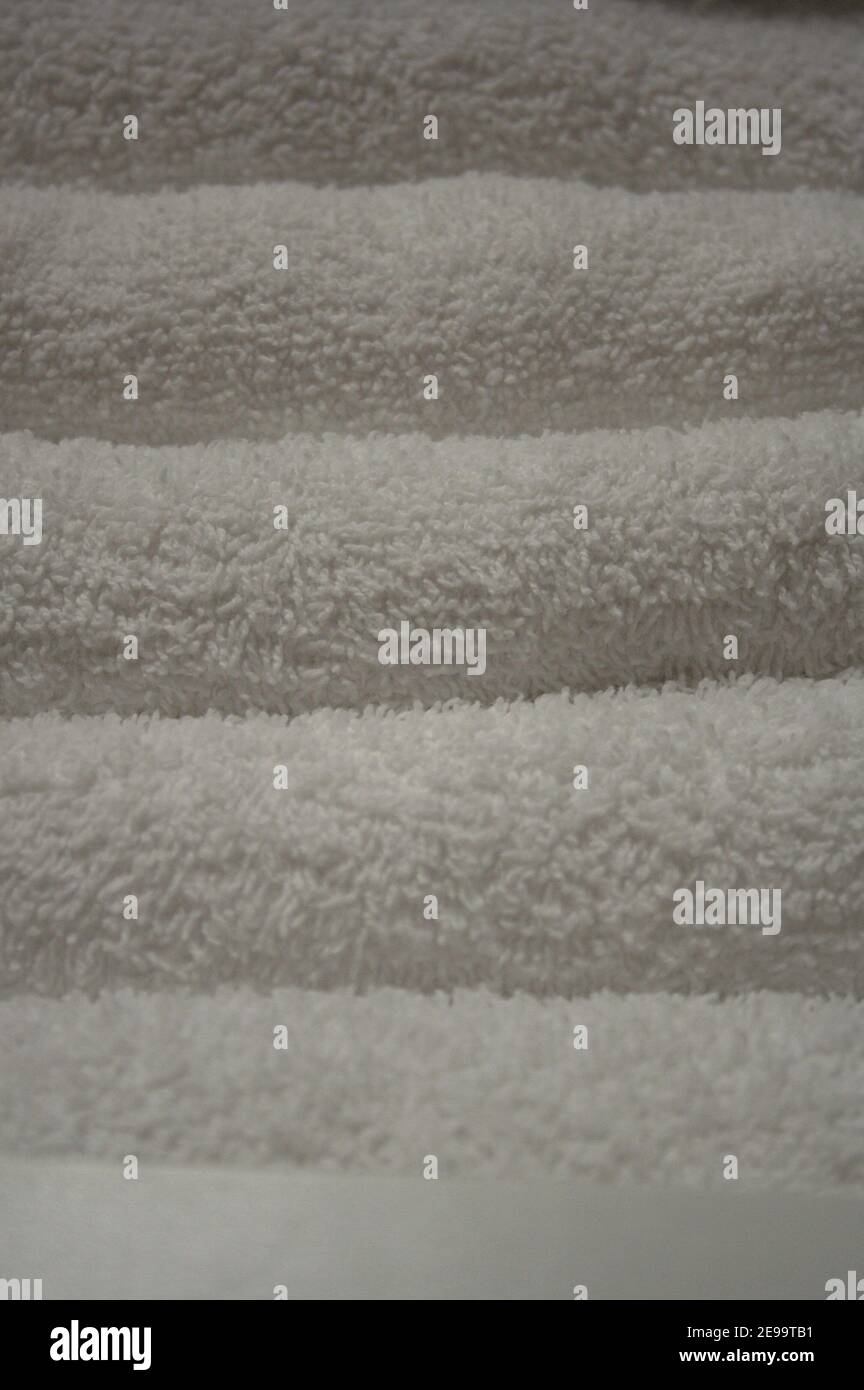 Nahaufnahme grobe Textur des Stoffes eines Stapels sauberer, weißer, fein gefalteter Handtücher. Stockfoto