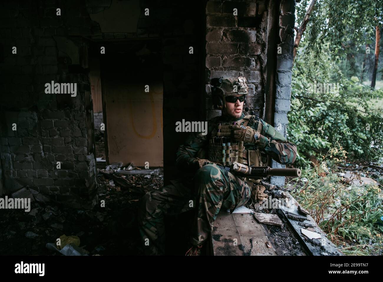 Ein nachdenklicher Soldat, der sich von einer Militäroperation ausruhte, während es draußen regnet. Stockfoto