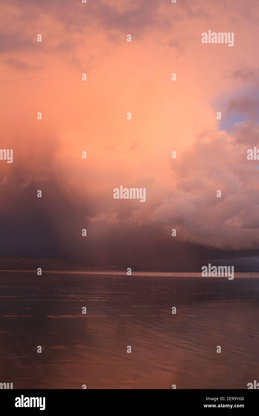 Storm Cloud formt sich am Strand von Black Rock Sands und erzeugt einen dramatischen Himmel, mit orange grauen Wolken, die eine unheimliche Szene erzeugen. Stockfoto