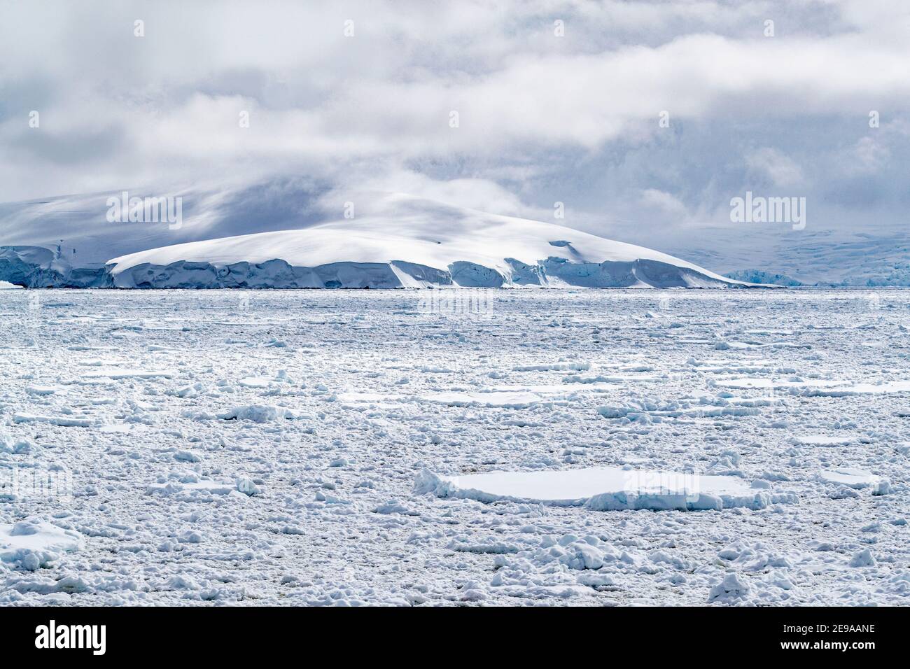 Schneebedeckte Berge und dichtes Meereis im Neumayer-Kanal, Palmer-Archipel, Antarktis. Stockfoto