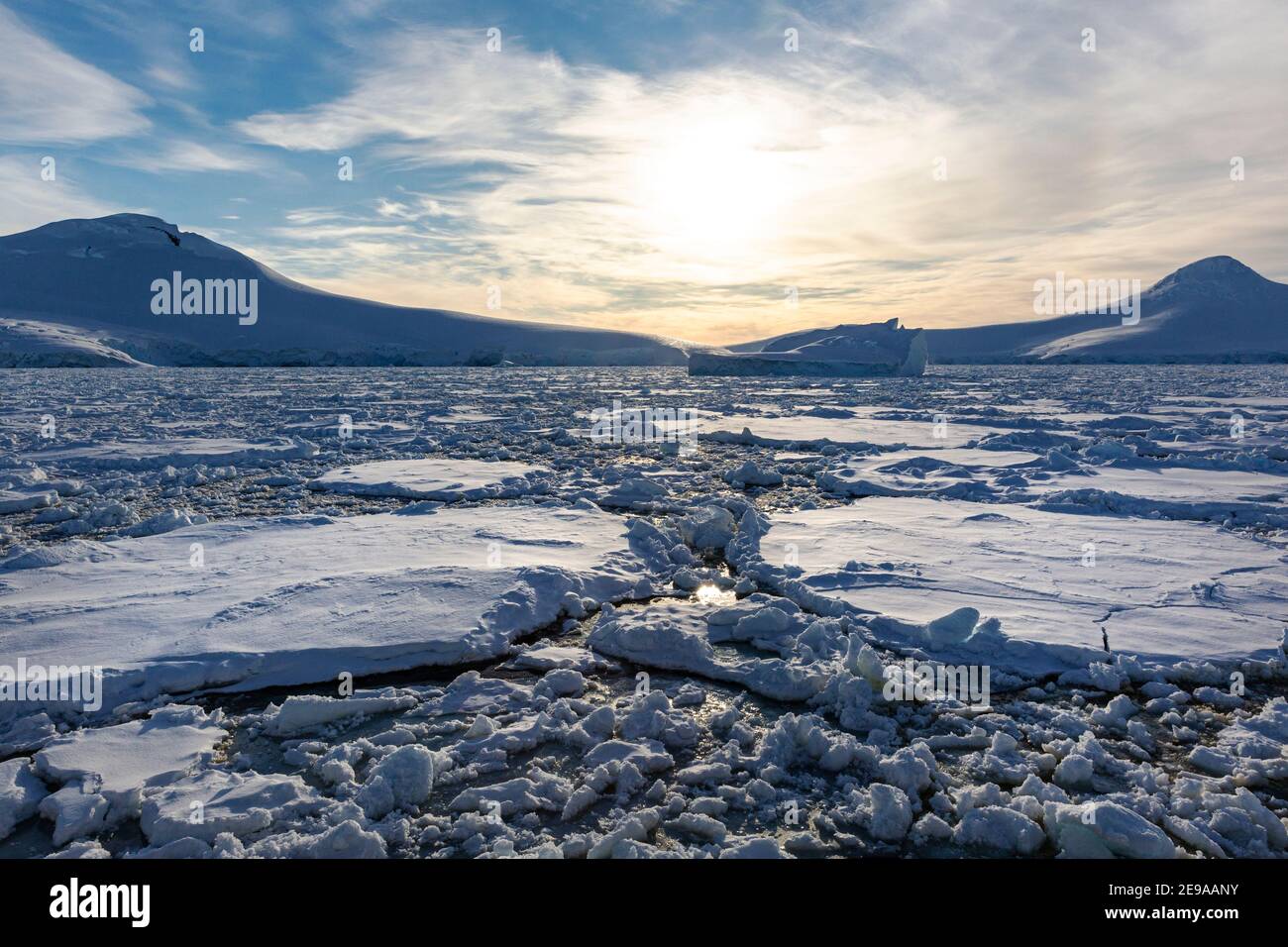 Schneebedeckte Berge und dichtes Meereis im Neumayer-Kanal, Palmer-Archipel, Antarktis. Stockfoto