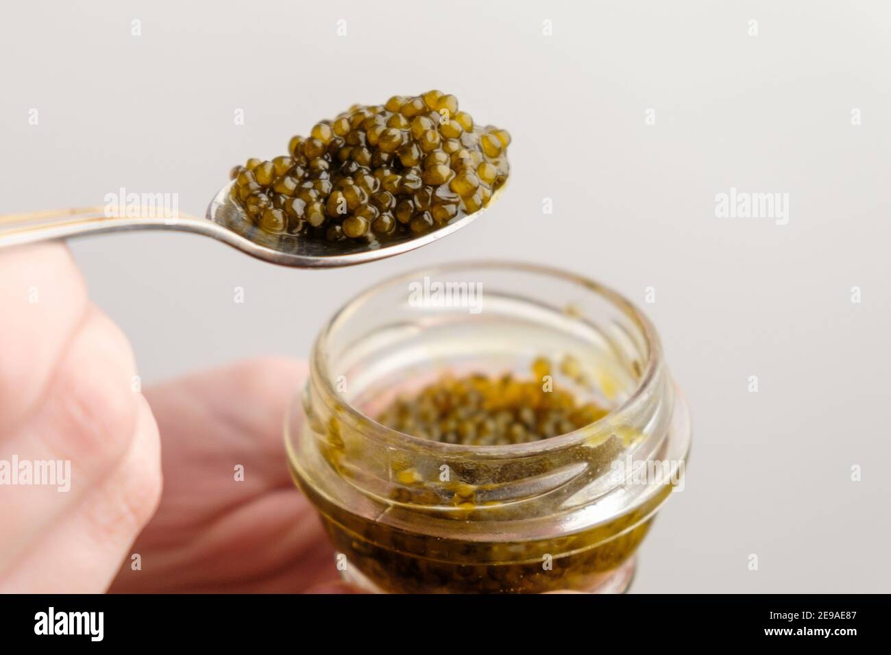 Schwarzer Stör-Kaviar in einem goldenen Löffel und Glas auf dem weißen Hintergrund mit Kopierraum. Stockfoto