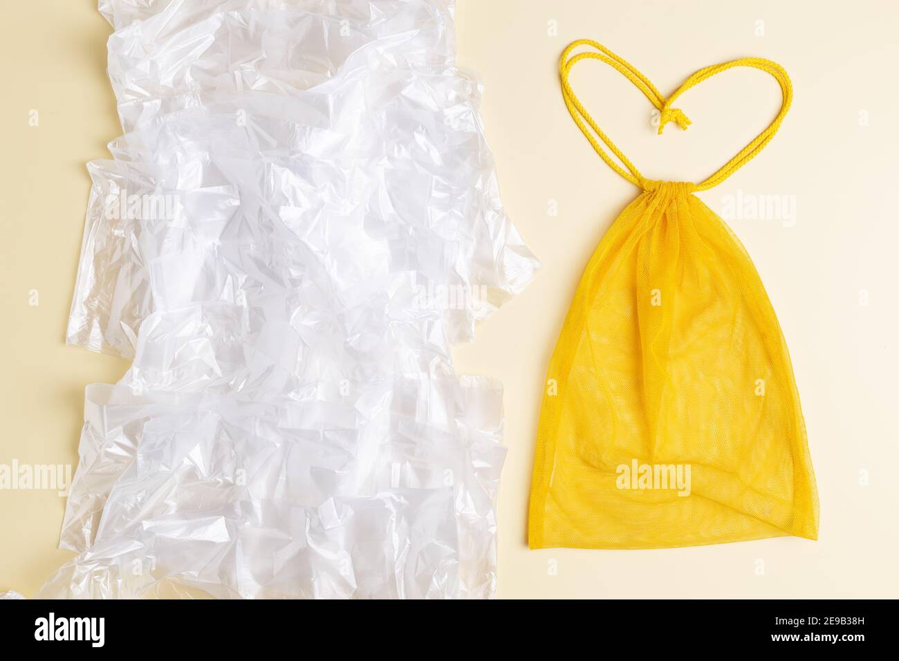 Wiederverwendbarer gelber Beutel in Form von Herz vs eine Menge Plastiktüten. Eco-Konzept. Kein Verschwendung einkaufen Stockfoto