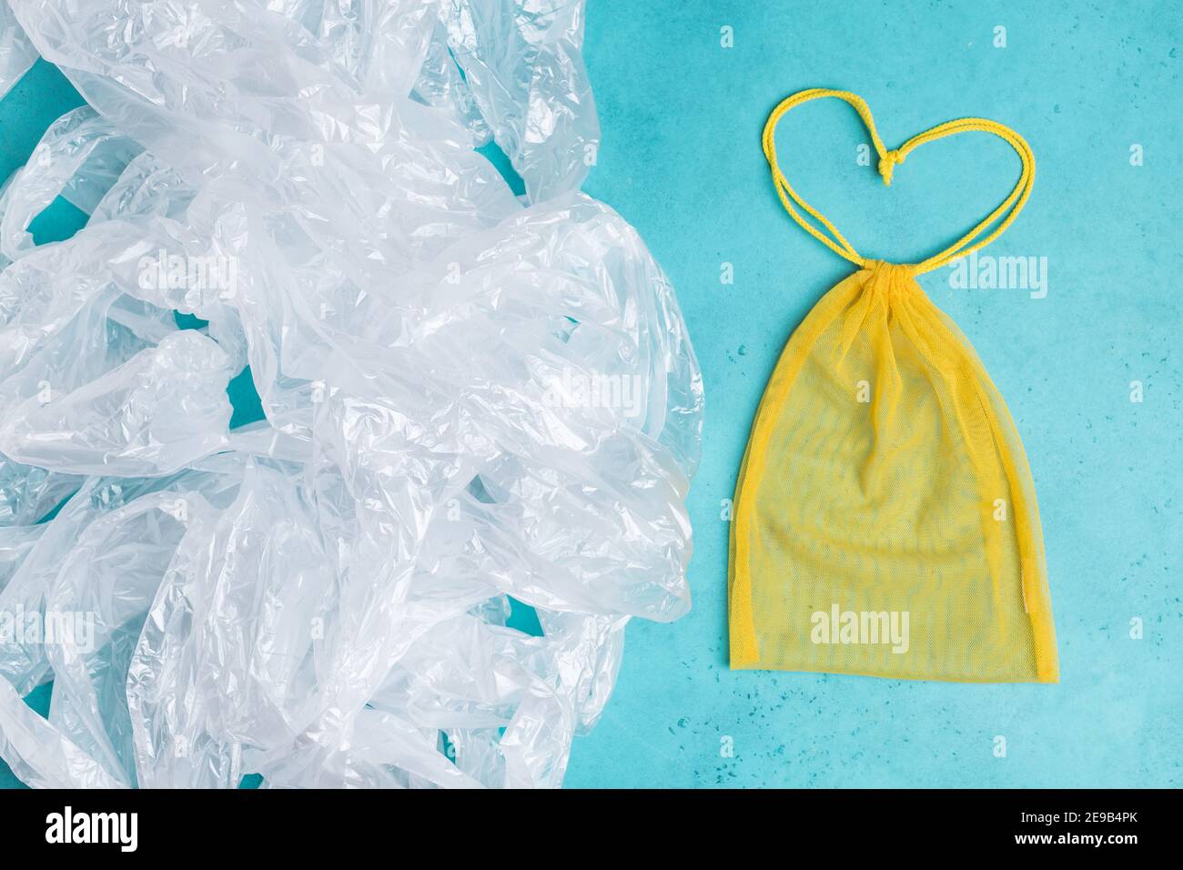 Wiederverwendbarer gelber Beutel in Form von Herz vs eine Menge Plastiktüten. Eco-Konzept. Kein Verschwendung einkaufen Stockfoto