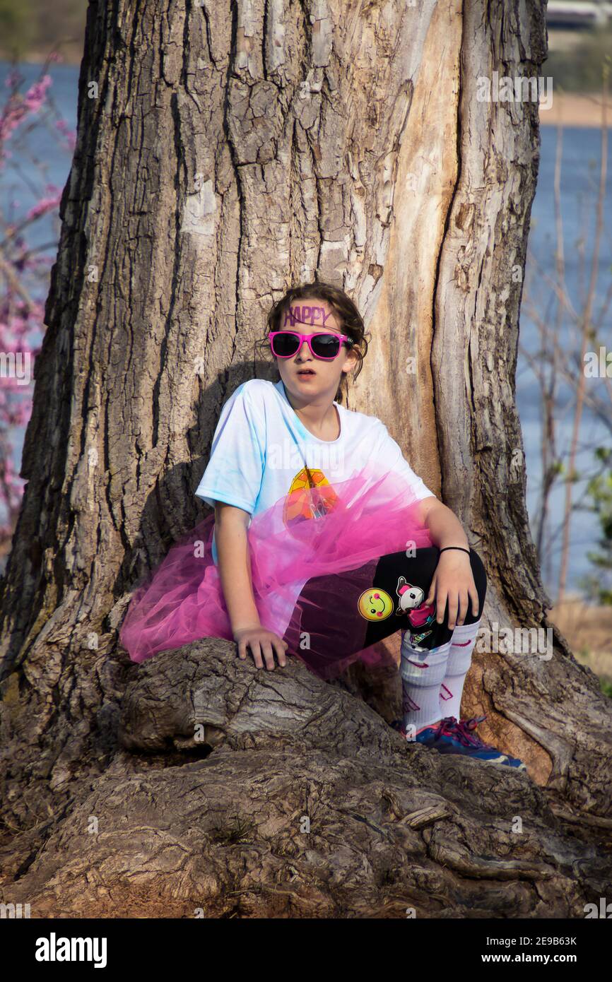 4-6-2019 Tulsa USA kleines Mädchen, das teilgenommen hat holi Farbe laufen mit leuchtend rosa Tutu und Sonnenbrille und Happy temporäre Tätowierung auf der Vorderhea Stockfoto