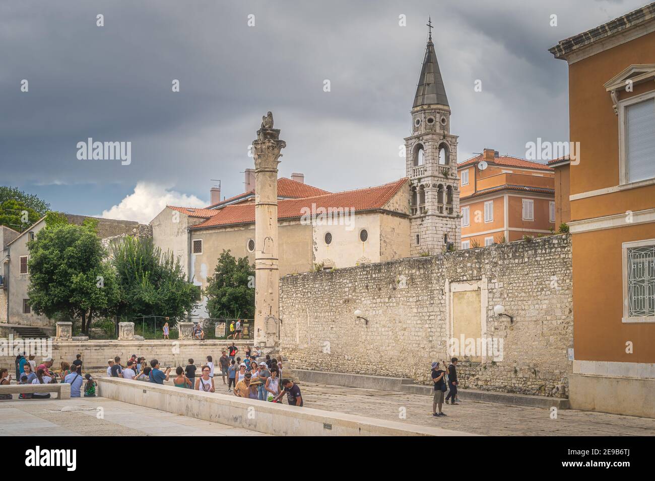 Zadar, Kroatien, Juli 2019 Touristen bewundern und fotografieren alte römische Ruinen, eine Säule mit Skulptur und St. Donata Kirche, Papst Johannes Paul II. Platz Stockfoto