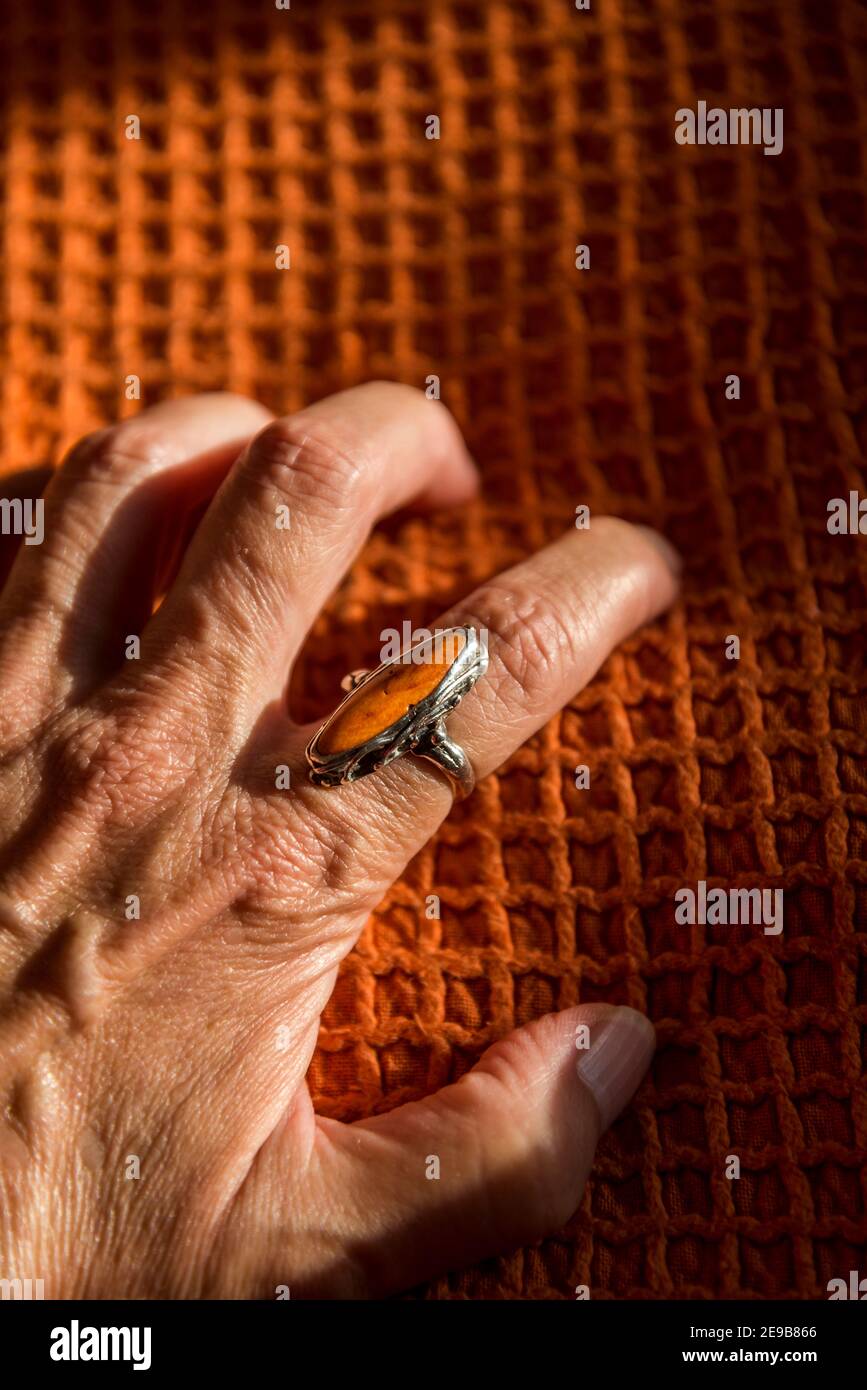 Weibliche Hand, die einen orangefarbenen Ring auf einem orangefarbenen Deckel ergreift Stockfoto