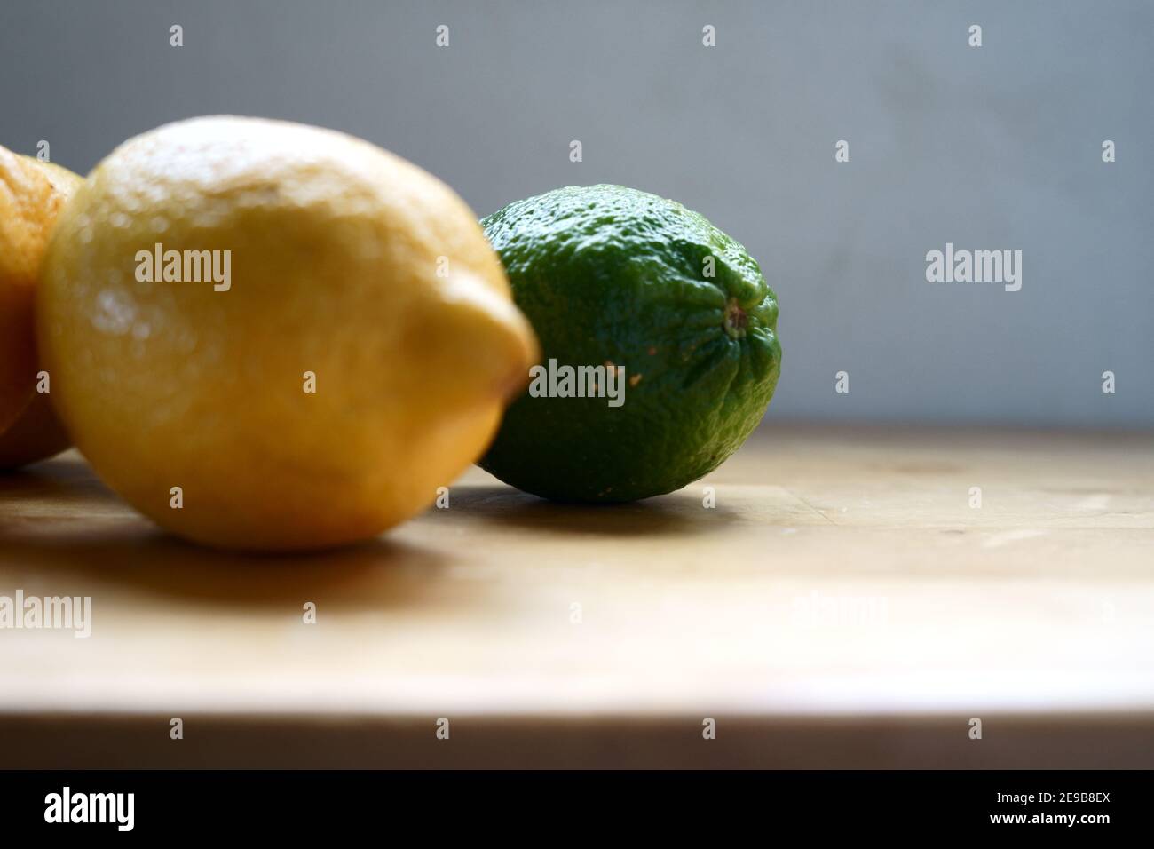 Portrait von frischen und biologischen Zutaten: Eine Reihe von Zitrone und Limette mit einem Fokus auf die frische und organische grüne Limette. Stockfoto