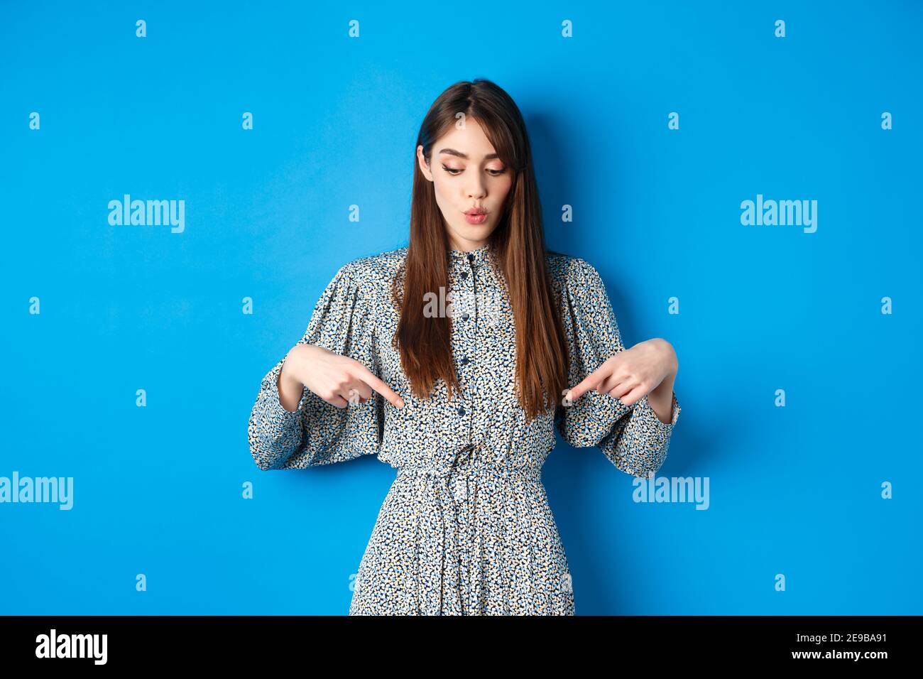 Fasziniert schöne Mädchen in Kleid sagen wow, Blick und zeigt auf Werbung,  zeigt promo mit interessierter Gesicht, blauer Hintergrund Stockfotografie  - Alamy