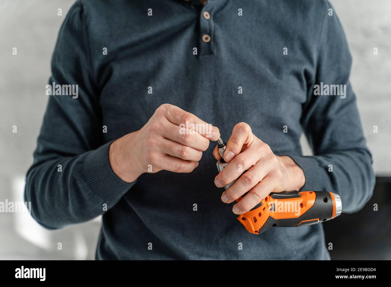 Vorderansicht Nahaufnahme der Hände eines erwachsenen kaukasischen Mannes Halten Sie den elektrischen Schraubendreher Stockfoto