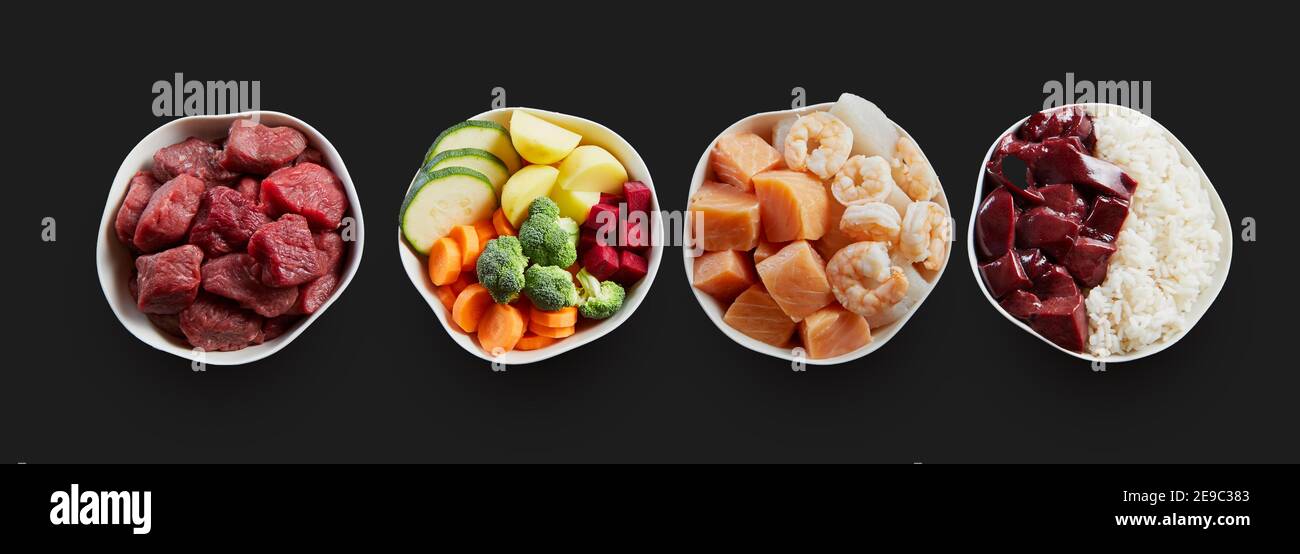 Tierernährung in einer Überkopfposition in einigen Schüsseln auf schwarzem Hintergrund in einem flachen Lay.Rindfleisch und vegane Ernährung für Hunde und Katzen. Stockfoto