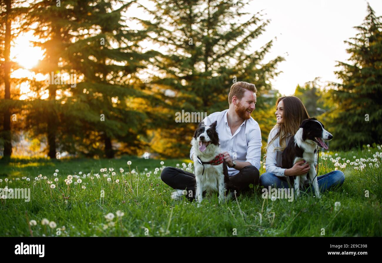 Glückliches junges Paar zu Fuß, spielen mit Hunden in einem Park Stockfoto