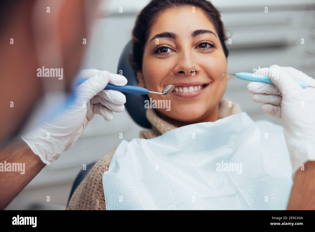 Lächelnde Frau, die ihre Zähne vom Zahnarzt überprüft. Frau mit zahnärztlichen Untersuchung in der Klinik. Stockfoto