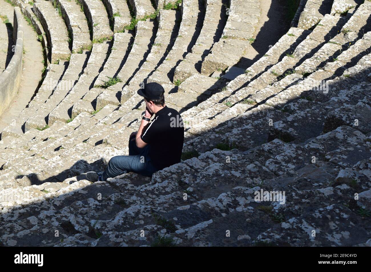 Ein junger Mann sitzt auf der römischen Theatertreppe in Djemila Stadt, Setif, Algerien Stockfoto