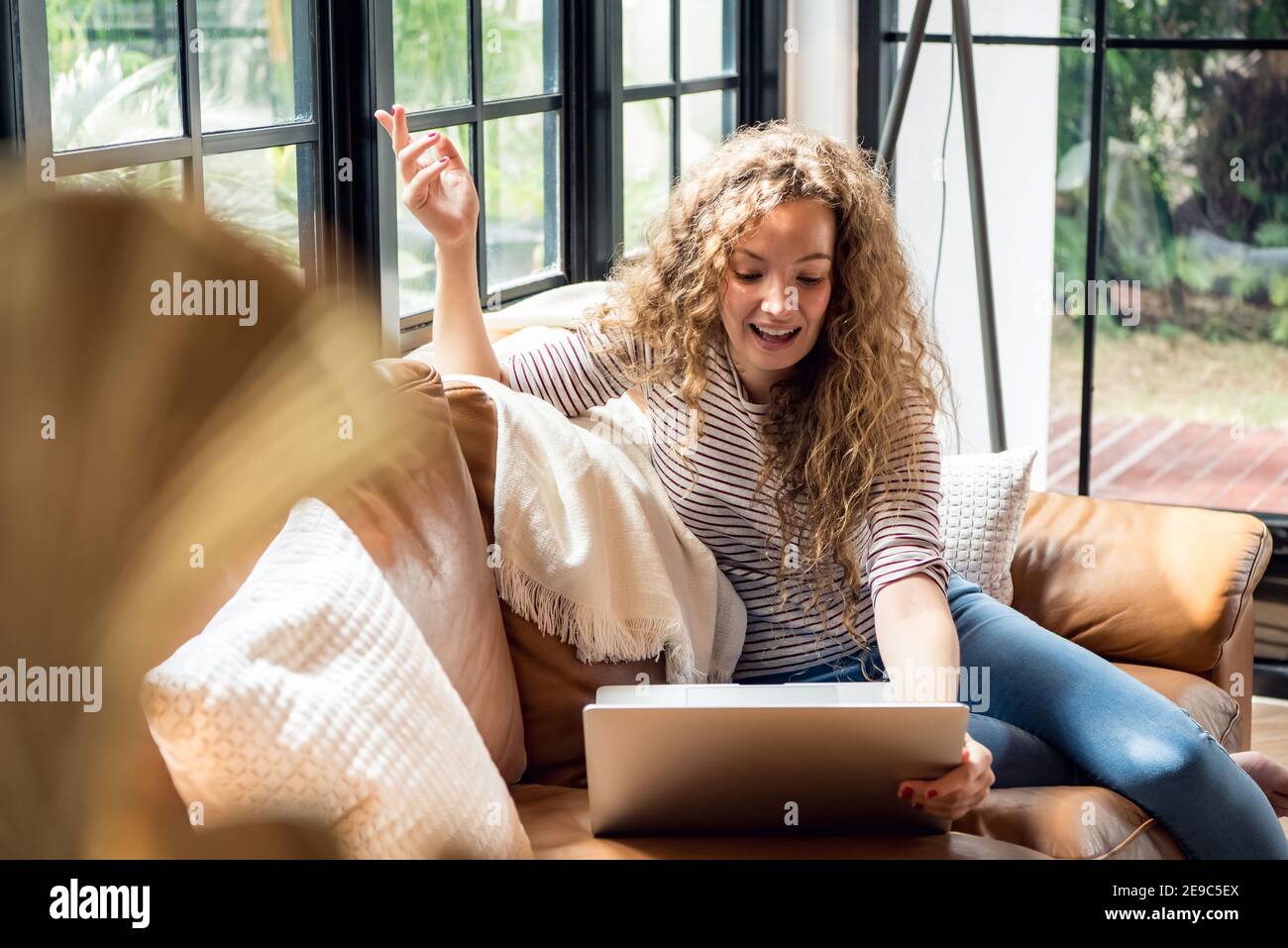 Hübsche kaukasische Frau chatten via Videoanruf online mit Laptop Computer, während Sie zu Hause auf der Couch sitzen Stockfoto