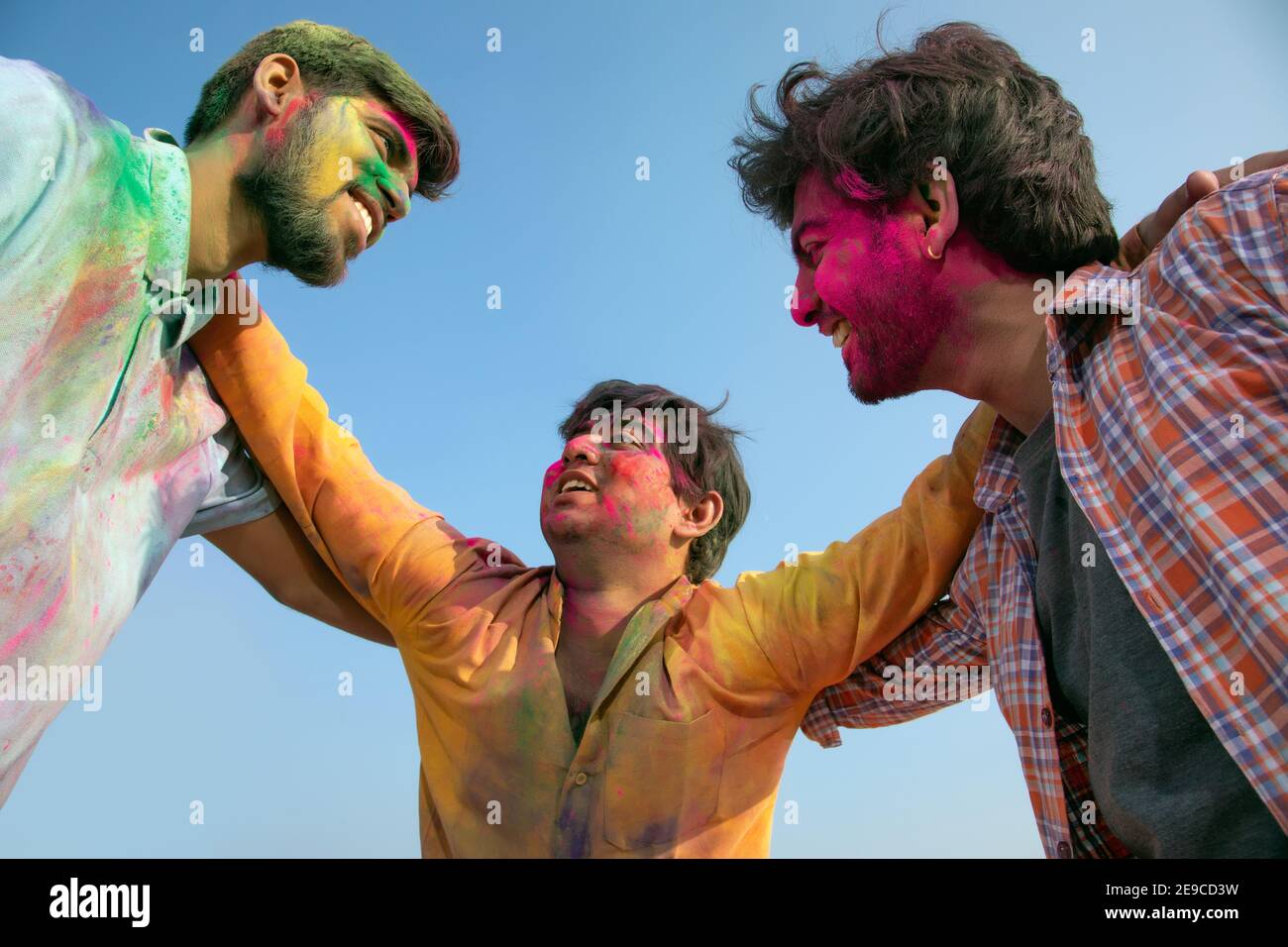 JUNGE MÄNNER SCHAUEN SICH GLÜCKLICH AN, WÄHREND SIE HOLI FEIERN Stockfoto