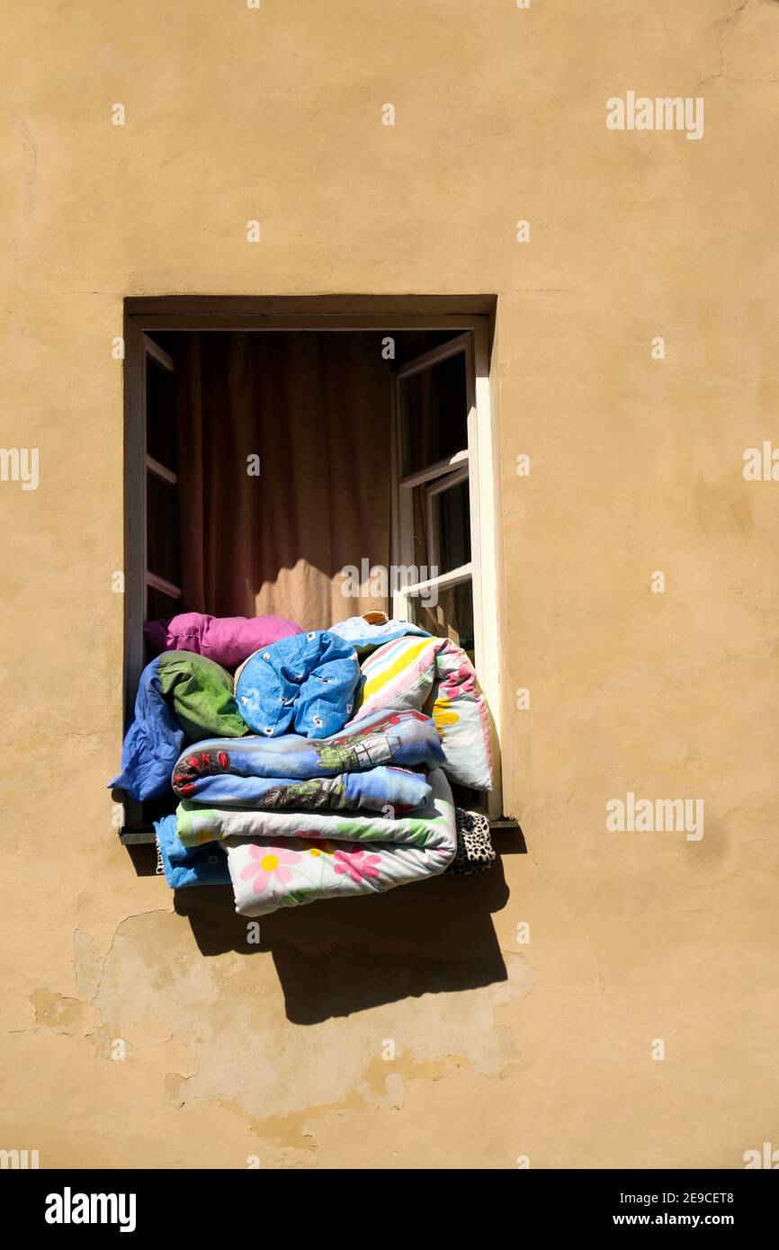 Ein Fenster voller farbenfroher Kissen und Bettdecken, die an der Sonne lüften. Stockfoto