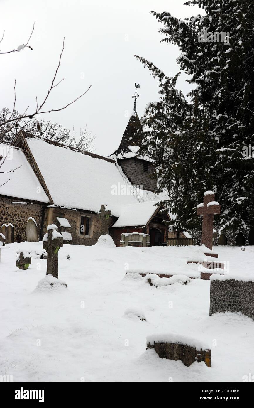 Kirche und Kirchhof von St. Nicholas, Pyrford, Surrey, im Winter in Großbritannien im Schnee Stockfoto