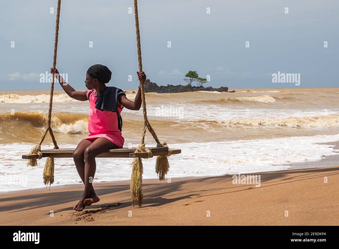 Afrikanische Frau sitzt am Meer auf einem Hängesessel. Axim Ghana West Africa Beach 2018 November 2 Stockfoto