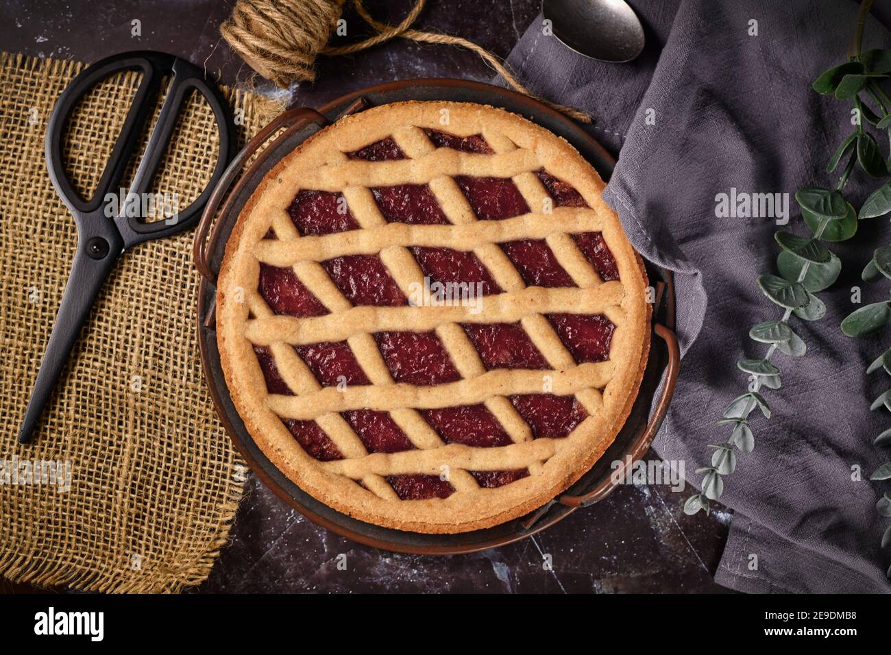 Draufsicht auf hausgemachten Kuchen namens "Linzer Torte", ein traditionelles österreichisches Shortcake-Gebäck mit Obstkonserven und in Scheiben geschnittenen Nüssen mit Gitterdessig gekrönt Stockfoto