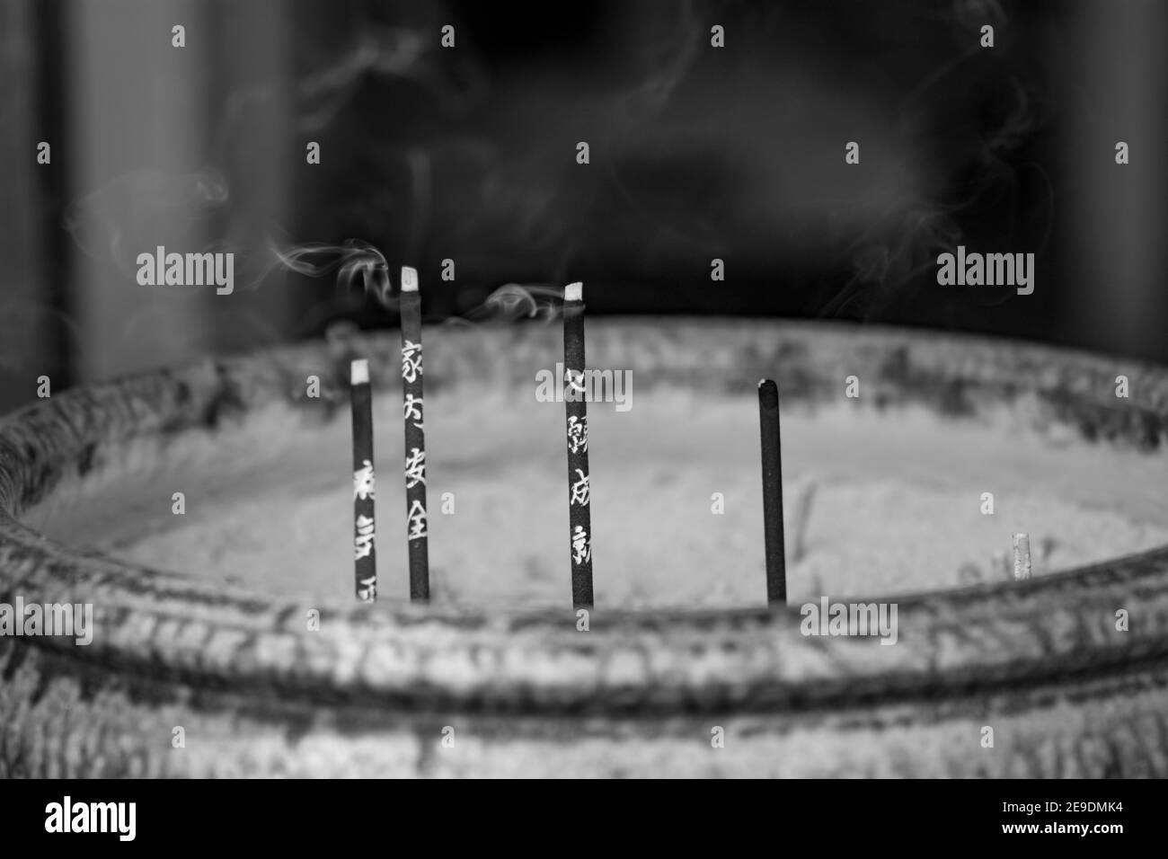 Graustufen-Aufnahme von Räucherstäbchen in einer großen Schüssel Stockfoto