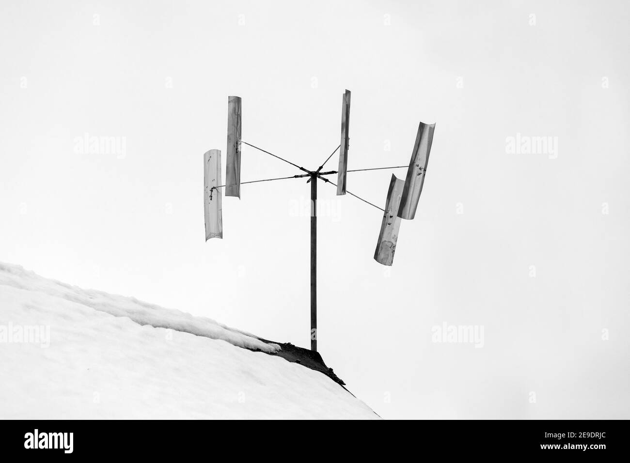 Windturbine auf einem Dach unter weißem Himmel Hintergrund montiert. Schwarzweiß-Foto Stockfoto