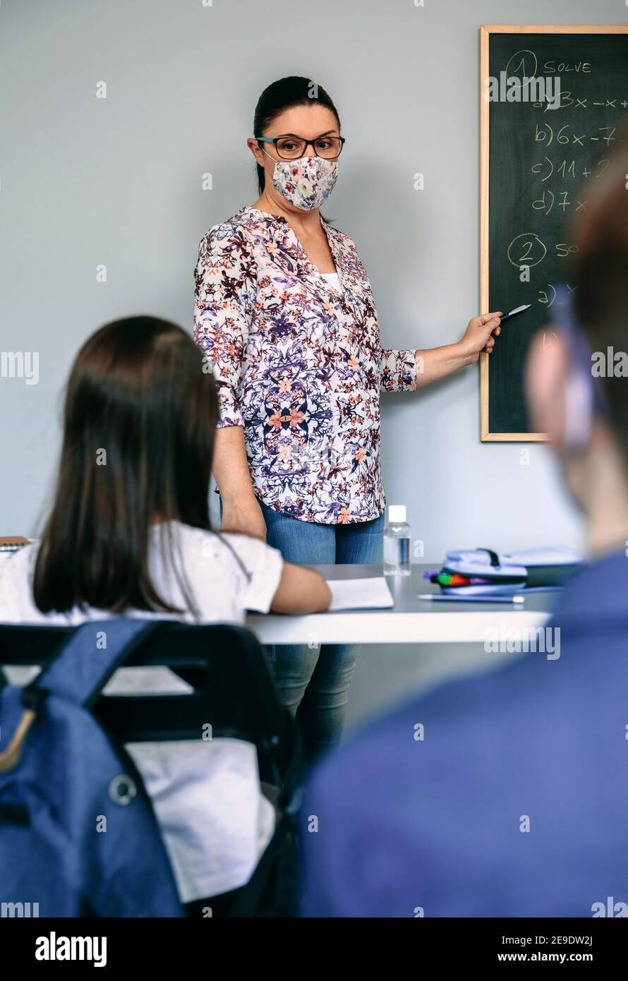 Lehrer mit Maske erklärt Übungen in Mathematik-Klasse Stockfoto