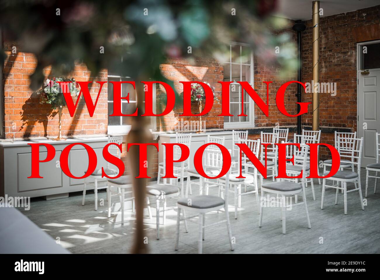 Hochzeit verschoben wegen Covid 19 Pandemie Sperrbeschränkungen rot Text und Bild des Trauungsraumes hinter leer schreiben Stühle keine Gäste Stockfoto