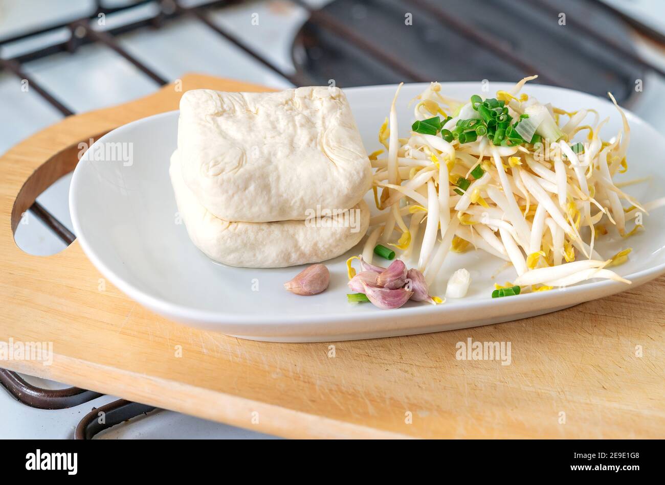 Bio-Bohnensprossen, Tofu, garlics und Schalotten in weißen Teller, die auf Holz Schneidebrett in der Küche, Konzept für die Küche gesunde vegetarische Lebensmittel Stockfoto