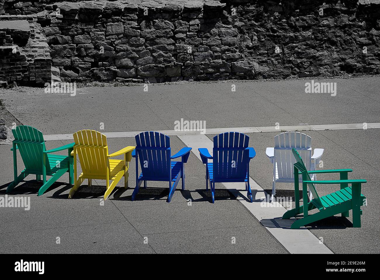 Farbenfrohe Adirondack-Stühle heben sich im Canal Basin in Buffalo, NY, in dieser selektiven Farbansicht ab. Stockfoto