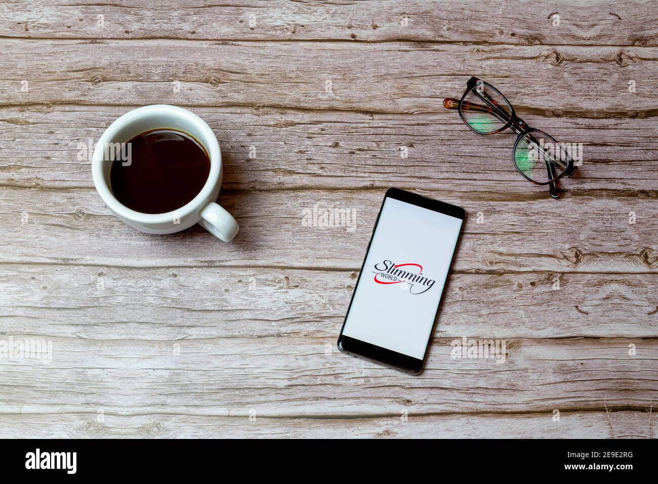 Ein Mobiltelefon oder Mobiltelefon auf einem Tisch Oder Schreibtisch mit der Slimming World App geöffnet und ein Kaffee daneben Stockfoto