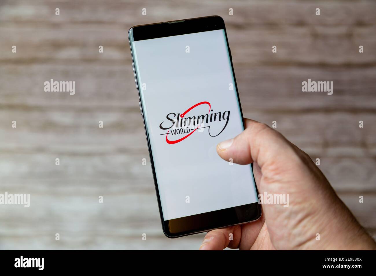 Eine Hand, die ein Mobiltelefon oder Mobiltelefon mit hält Die Schlankheits Welt Diät-App auf dem Bildschirm Stockfoto