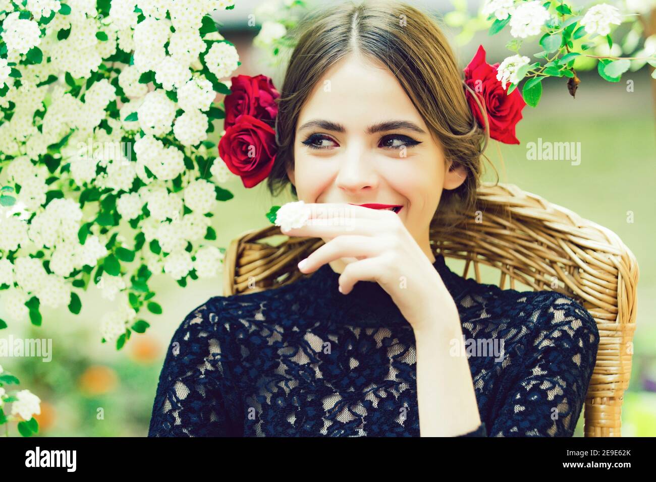 Schönheit spanisch Teenager Mädchen im Freien in blühenden Bäumen. Frühling Frau lächelt mit weißen Blume im Mund. Stockfoto