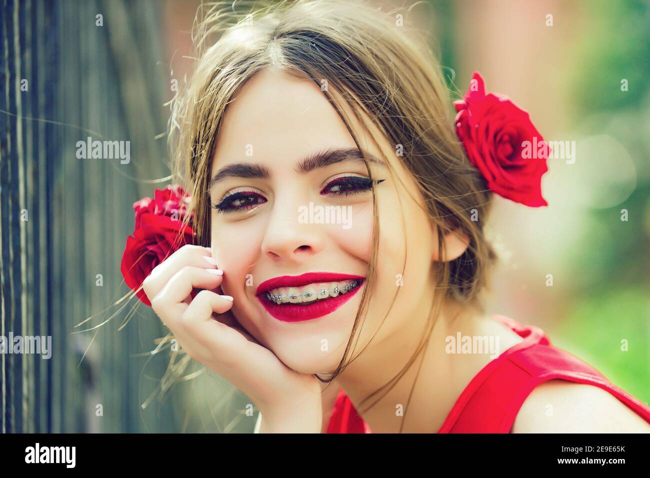 Nettes spanisches Teenager Mädchen mit roten Lippen und Rosen im Haar. Glückliches Gesicht. Stockfoto