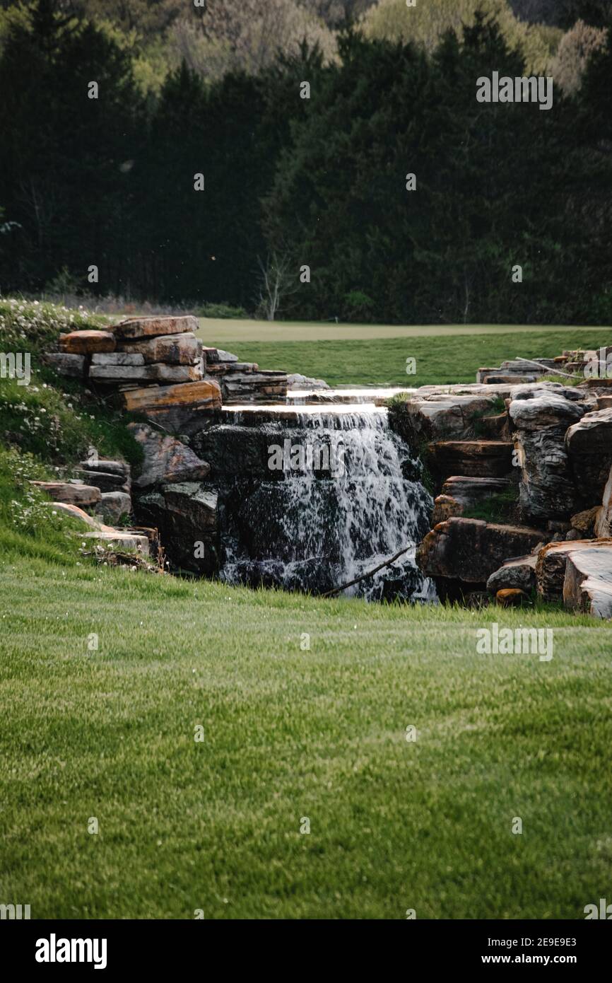 Vertikale Aufnahme eines kleinen Wasserstroms, der herunterfließt Zu einem Loch im Garten Stockfoto