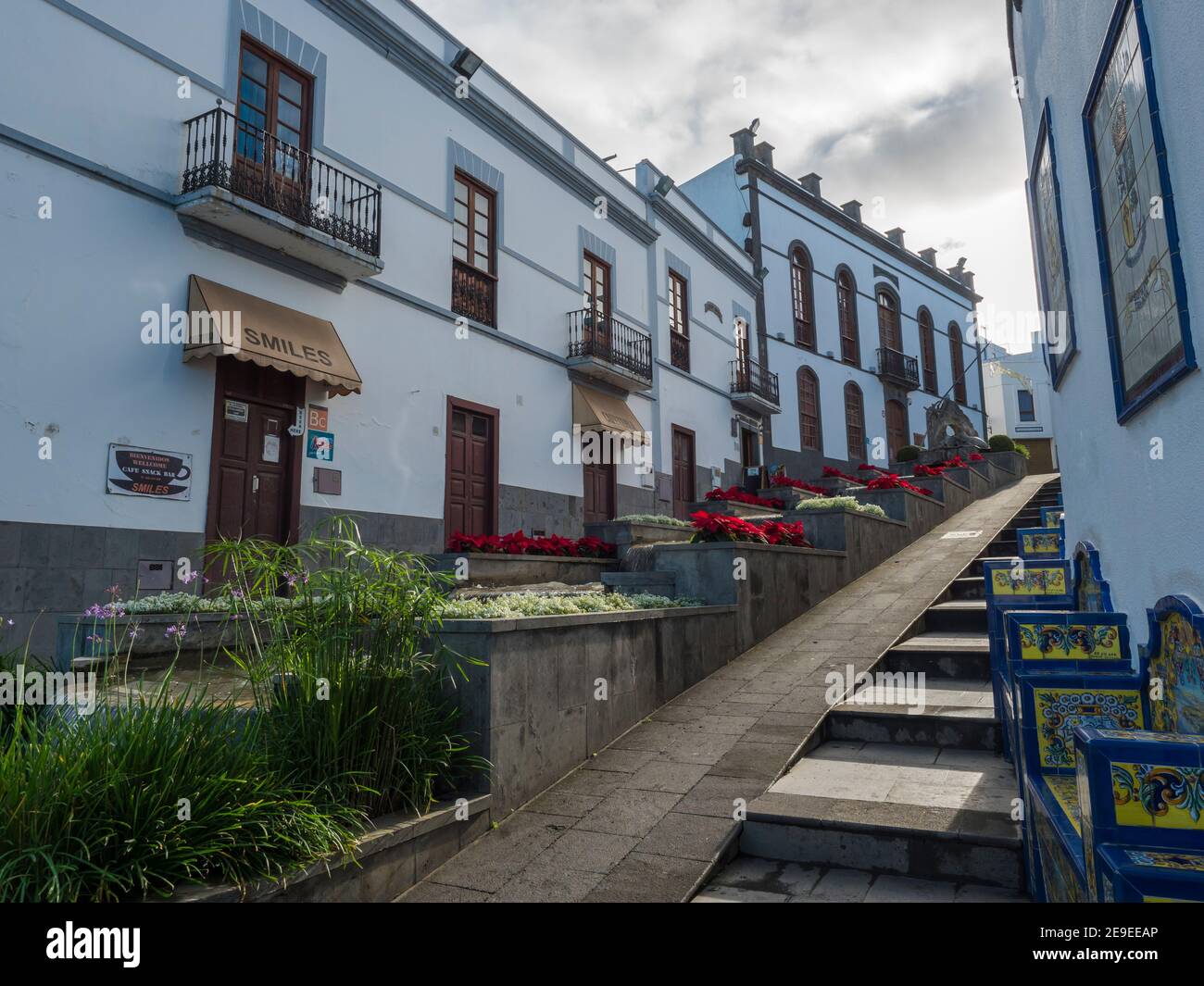 Firgas, Gran Canaria, Kanarische Inseln, Spanien 13. Dezember 2020: Blick auf die Straße Paseo de Gran Canaria mit Wasserfall Brunnen, Blumen und Keramik Stockfoto