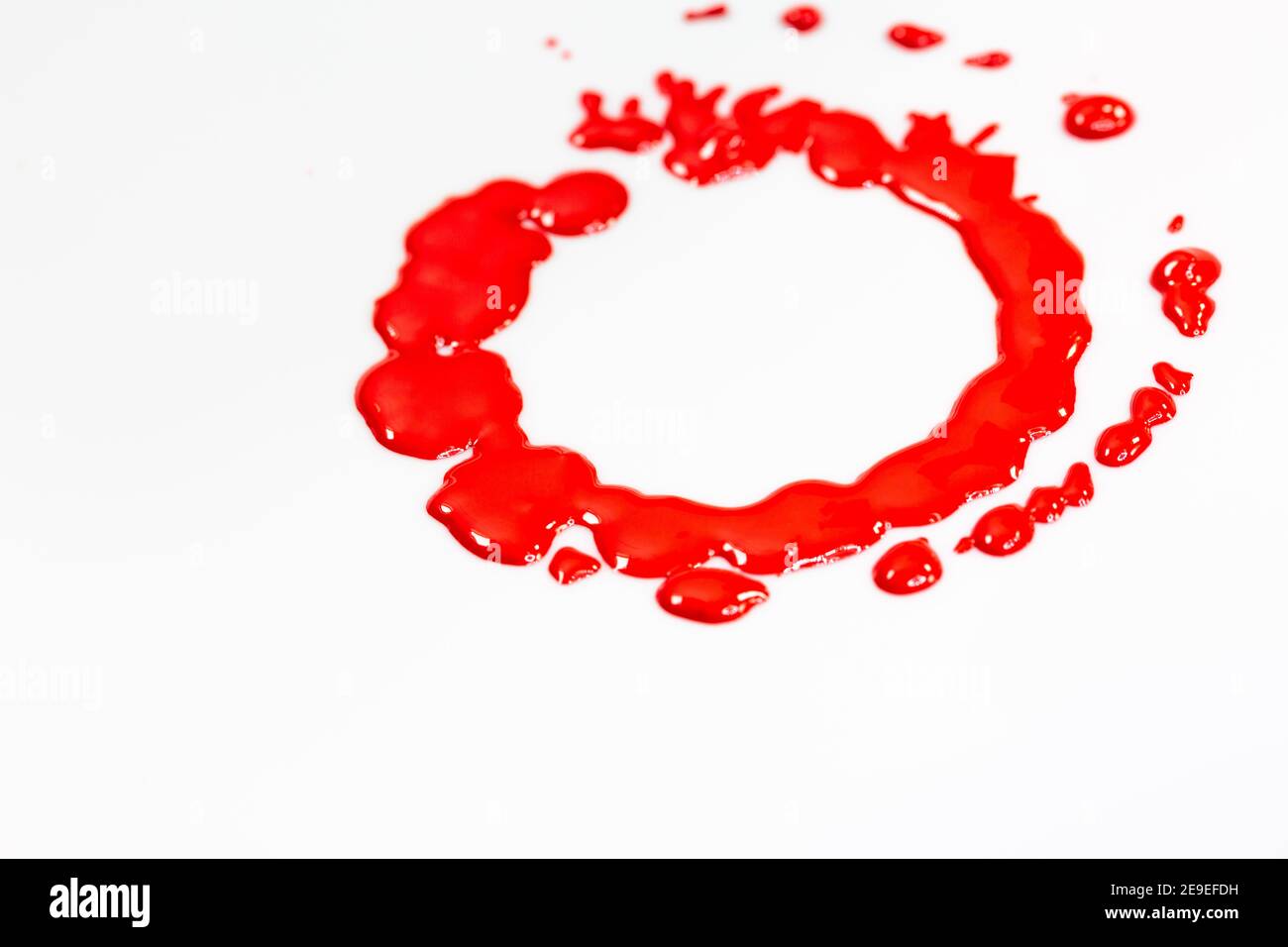 Rote Tinte tropft Kreise auf dem Boden eines rotierenden weißen Objekts. Stockfoto