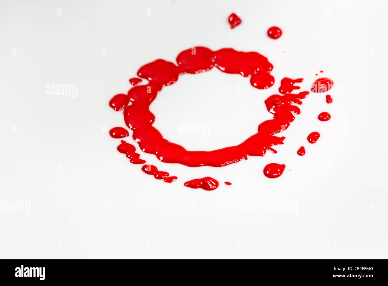Rote Tinte tropft Kreise auf dem Boden eines rotierenden weißen Objekts. Stockfoto