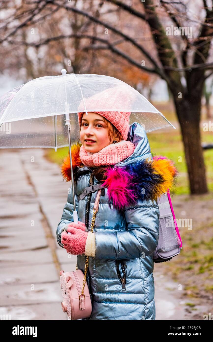 Mädchen in einer Jacke mit einem transparenten Regenschirm im Regen in der  Kälte. Teenager unter einem Regenschirm Stockfotografie - Alamy