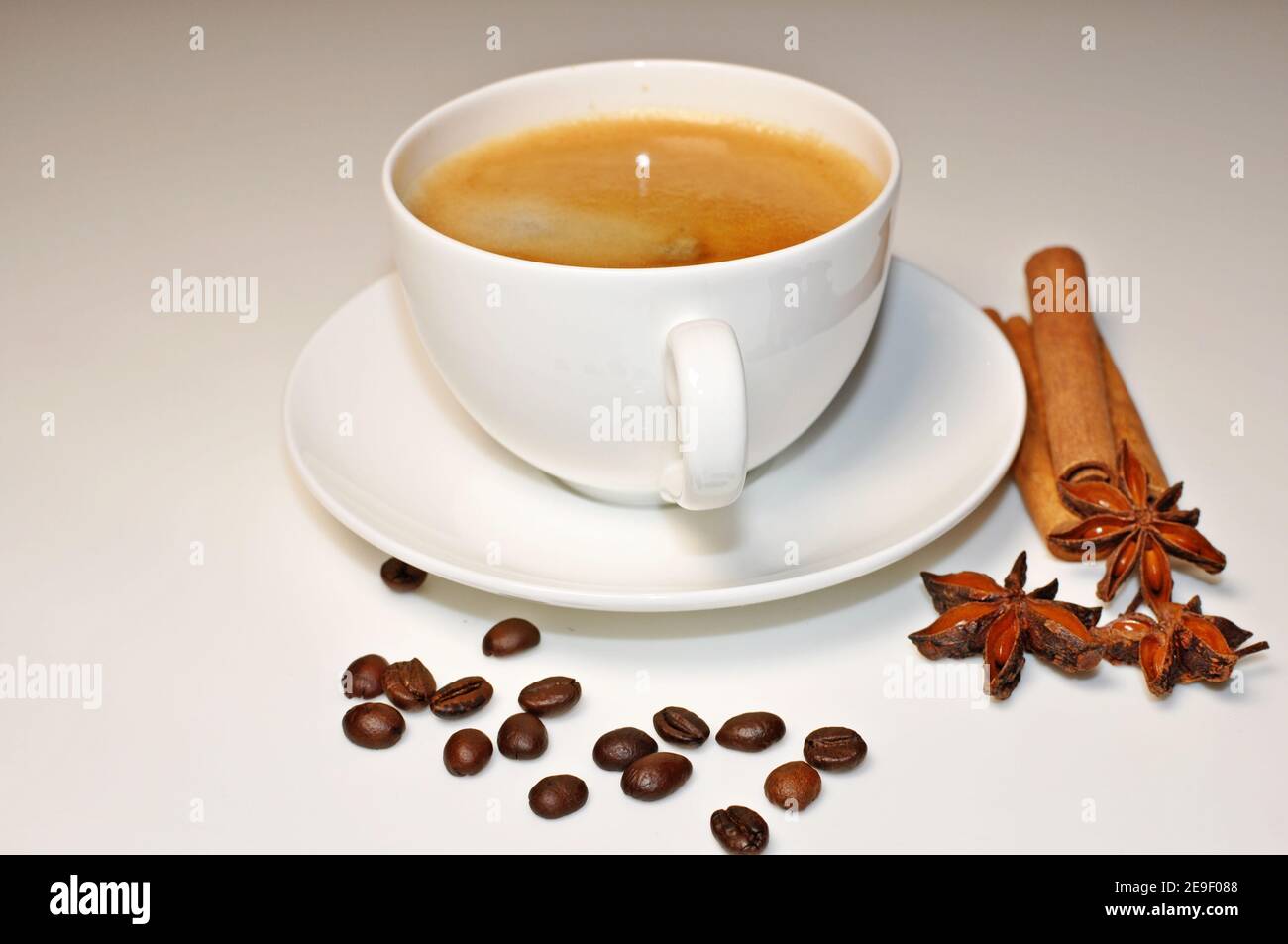 Tasse heißen Kaffee mit Zimt, Kaffeebohnen und Anis Stern Dekoration auf weißem Tischhintergrund. Stockfoto