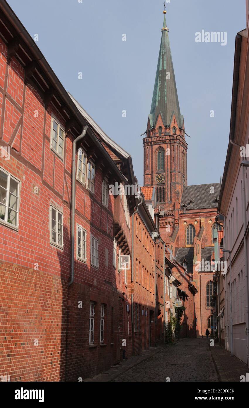 Die Kirche St. Nicolai, die im 15. Jahrhundert im gotischen Backsteinstil erbaut wurde, und eine kleine Gasse mit historischen Ziegelsteinhäusern. Lüneburg, Deutschland. Stockfoto