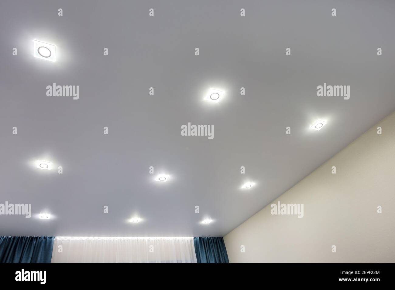 Abgehängte Decke mit Halogenstrahlern und Trockenmauerkonstruktion im leeren Raum in Wohnung oder Haus. Stretchdecke weiß und komplex. Stockfoto