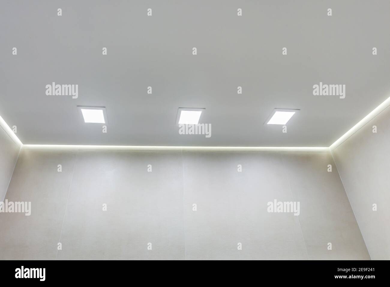 Abgehängte Decke mit Halogenstrahlern und Trockenmauerkonstruktion im leeren Raum in Wohnung oder Haus. Stretchdecke weiß und komplex. Stockfoto