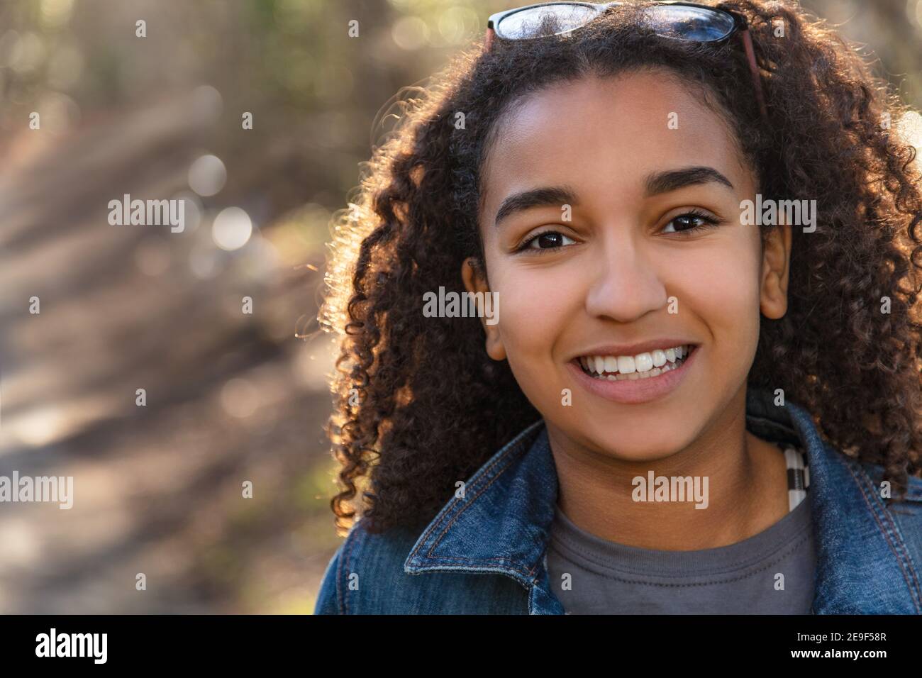 Outdoor Portrait der schönen glücklich gemischt Rennen afroamerikanische Mädchen Teenager weibliche junge Frau Lächeln mit perfekten Zähnen Stockfoto