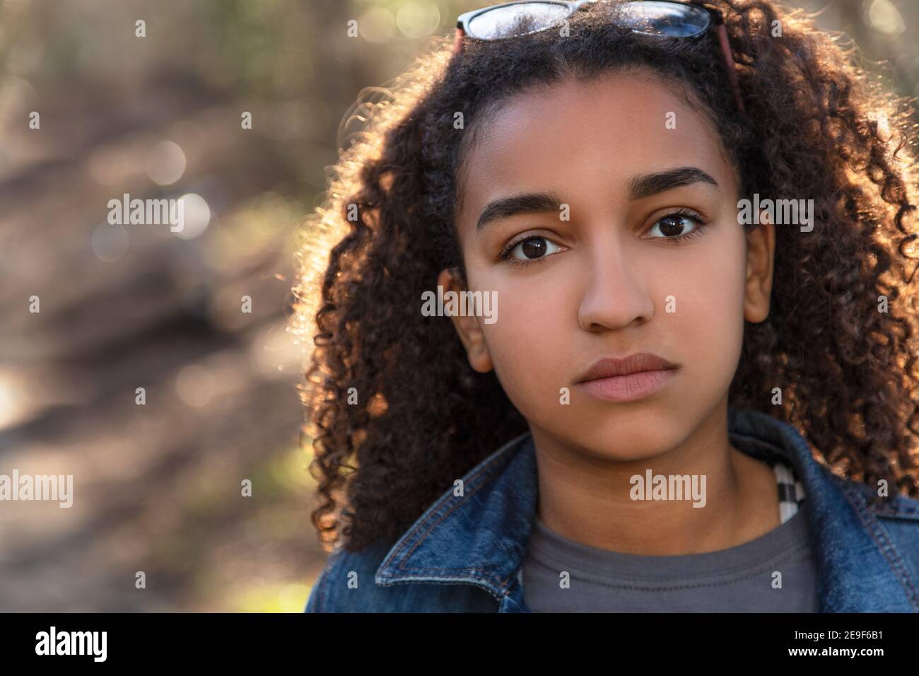 Outdoor-Porträt von schönen glücklich gemischte Rasse afroamerikanische Mädchen Teenager weibliches Kind, das nachdenklich oder traurig aussieht Stockfoto