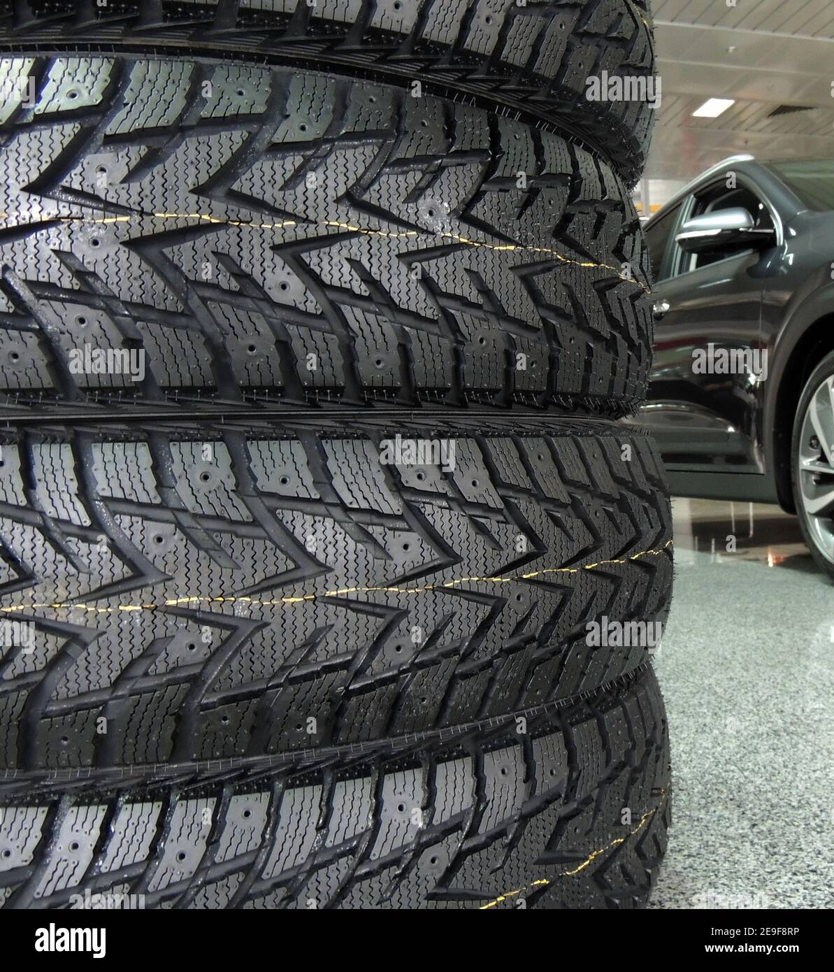 Gestapelte Reifen vor dem Fahrzeug im Ausstellungsraum des Händlerbetriebs Stockfoto