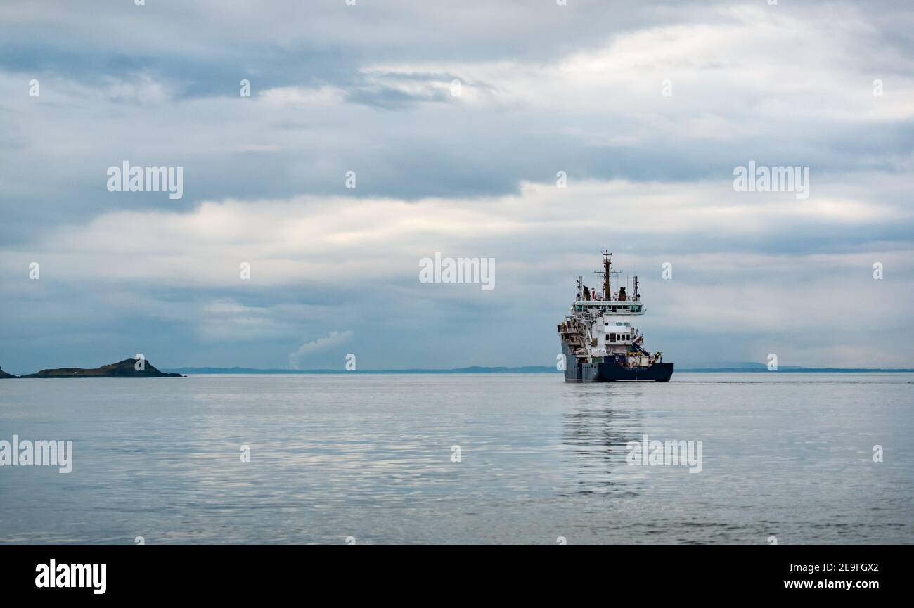 Moody Ansicht von Versorgungsschiff in ruhigem Wasser mit bewölktem Himmel, Firth of Forth, Schottland, UK Stockfoto